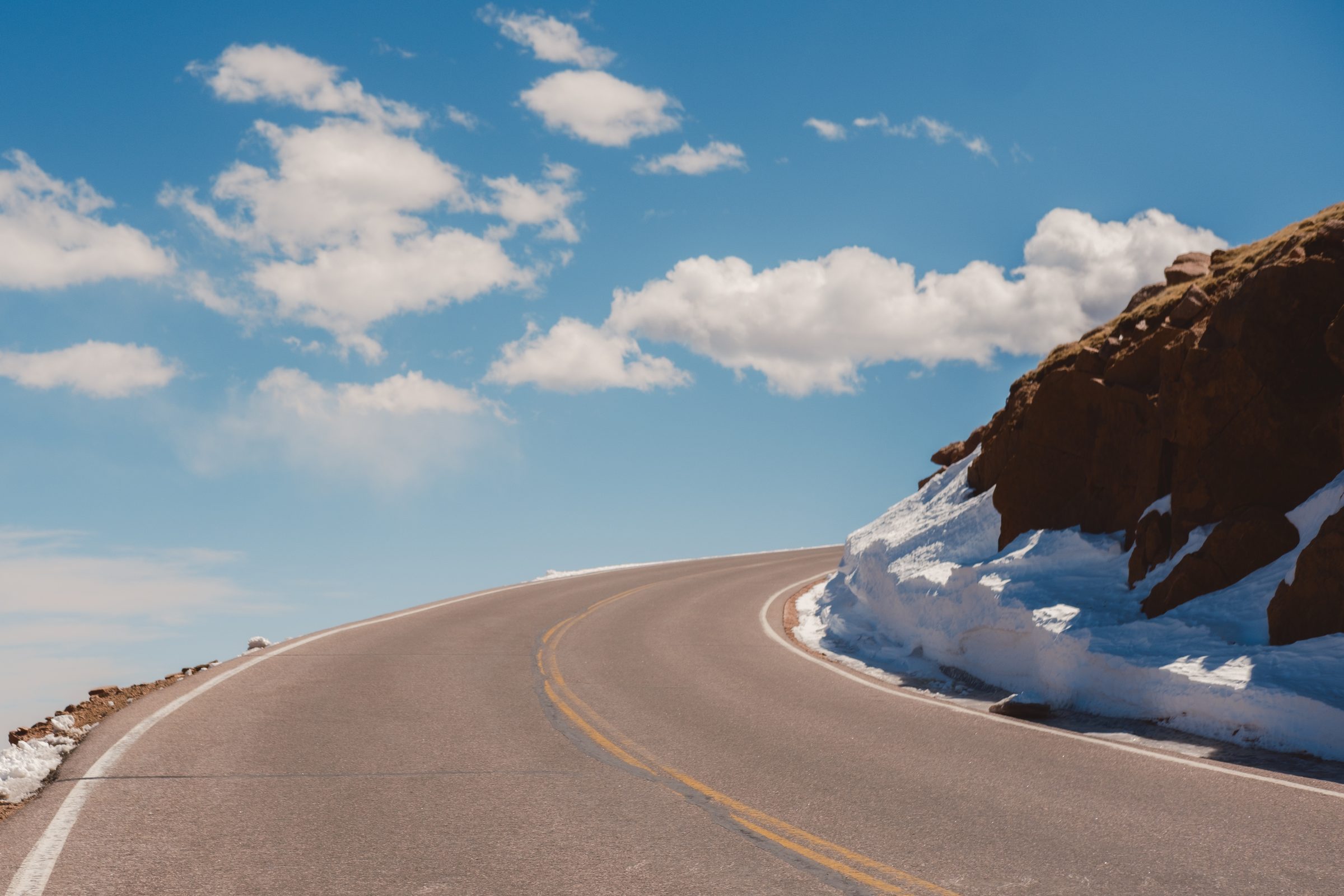 A curve on the Pikes Peak Highway beneath open sky and clouds