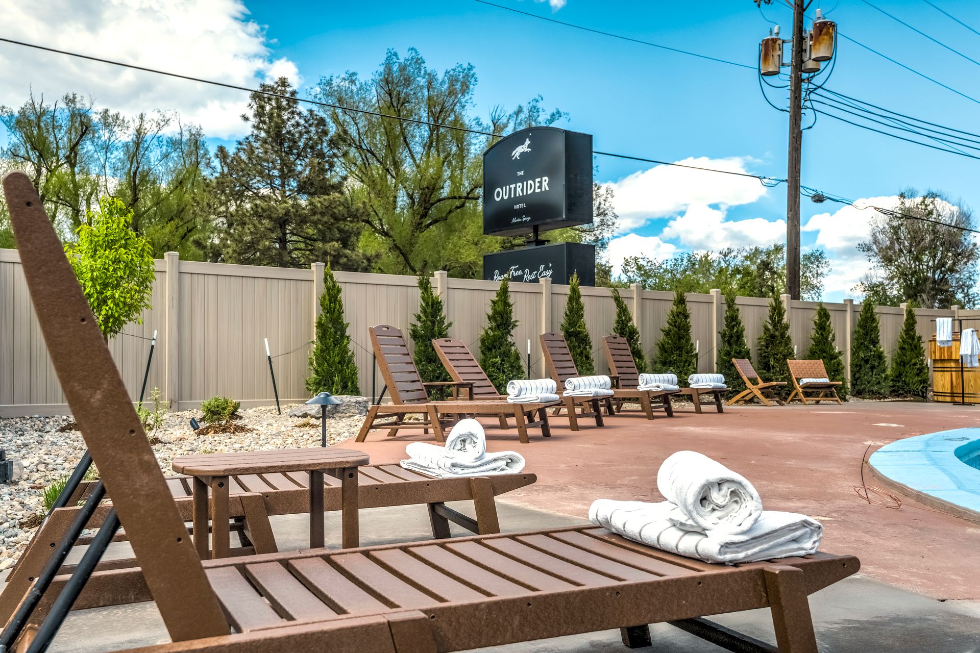 Poolside loungers with fresh towels on the patio at The Outrider Hotel